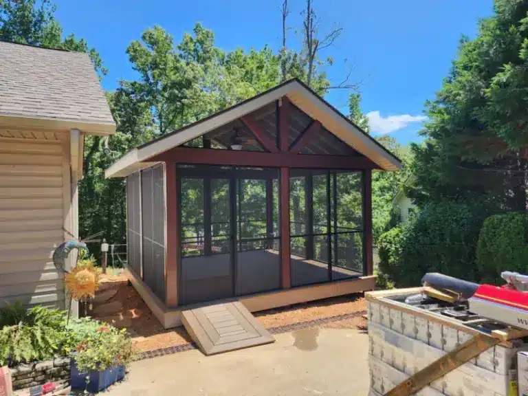 Freestanding screened gazebo with gable roof, dark trim, composite deck floor, and ceiling fan in a backyard.